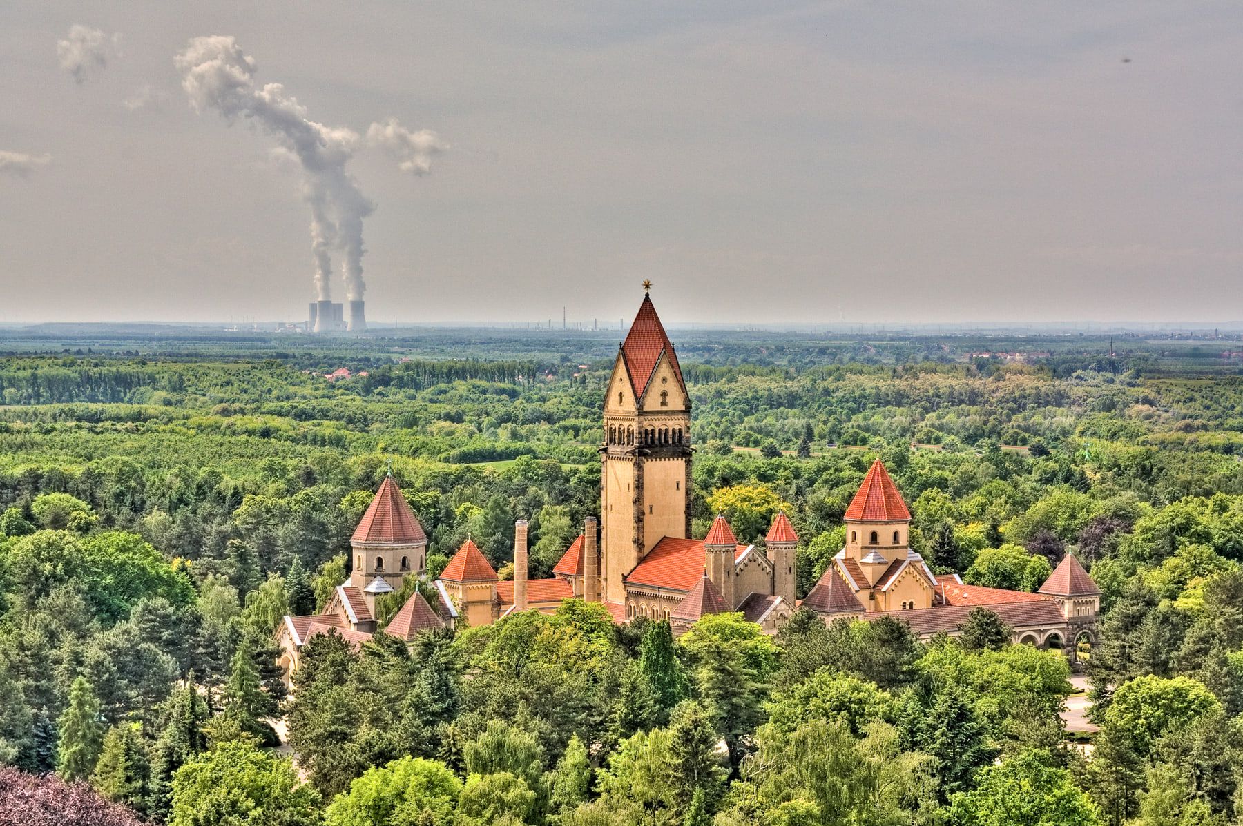 Blick von oben auf die Kapellenanlage mit hohem Mittelturm über dichtem Grün auf Südfriedhof Leipzig