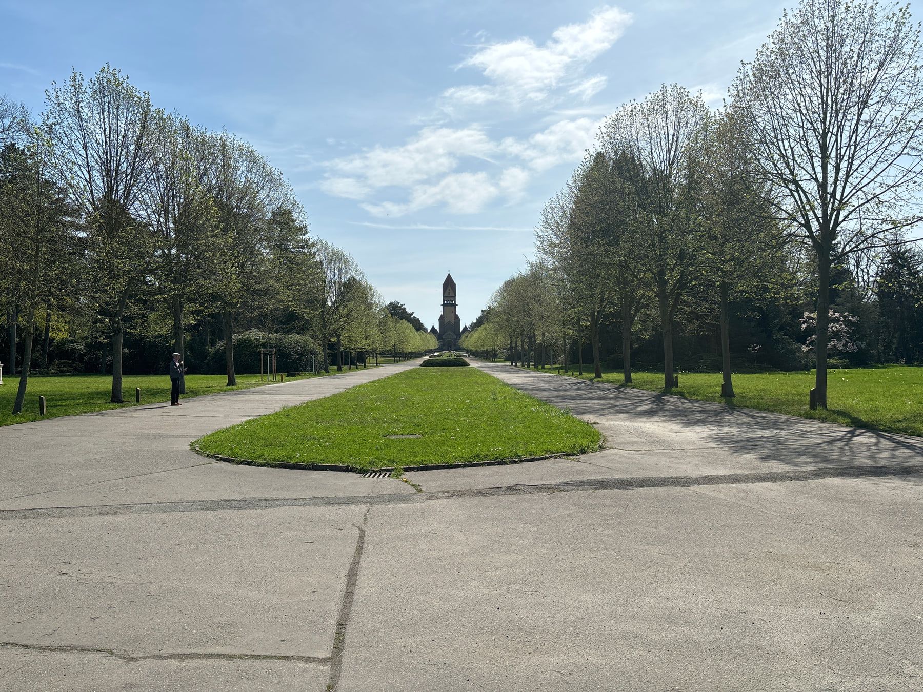Gerade baumbestandene Hauptachse mit grüner Mittelinsel zur Kapellenanlage auf Südfriedhof Leipzig