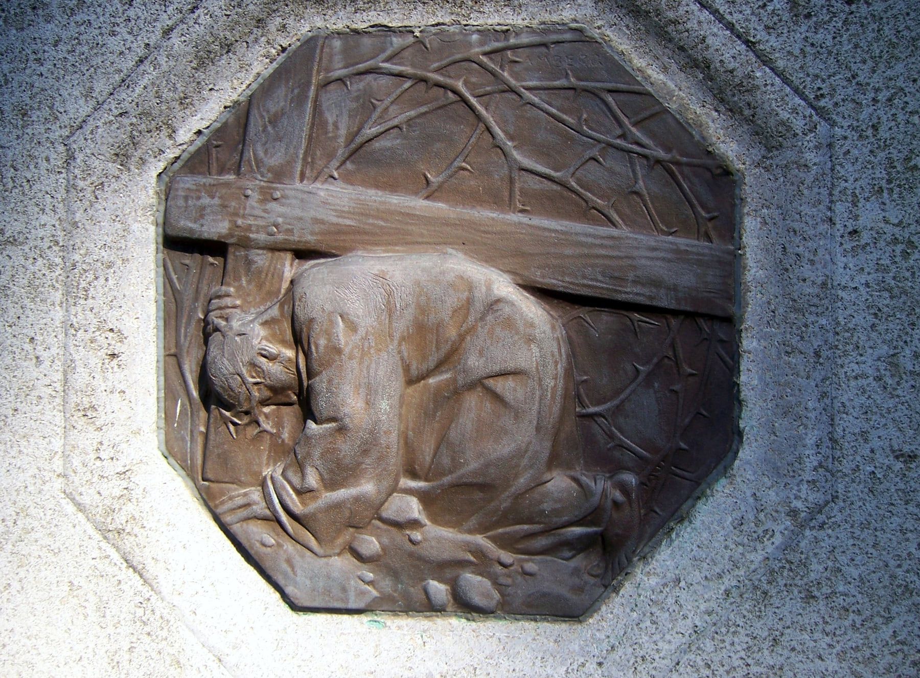 Bronzerelief eines unter dem Kreuzbalken knienden Christus zwischen Dornenzweigen auf Südfriedhof Leipzig
